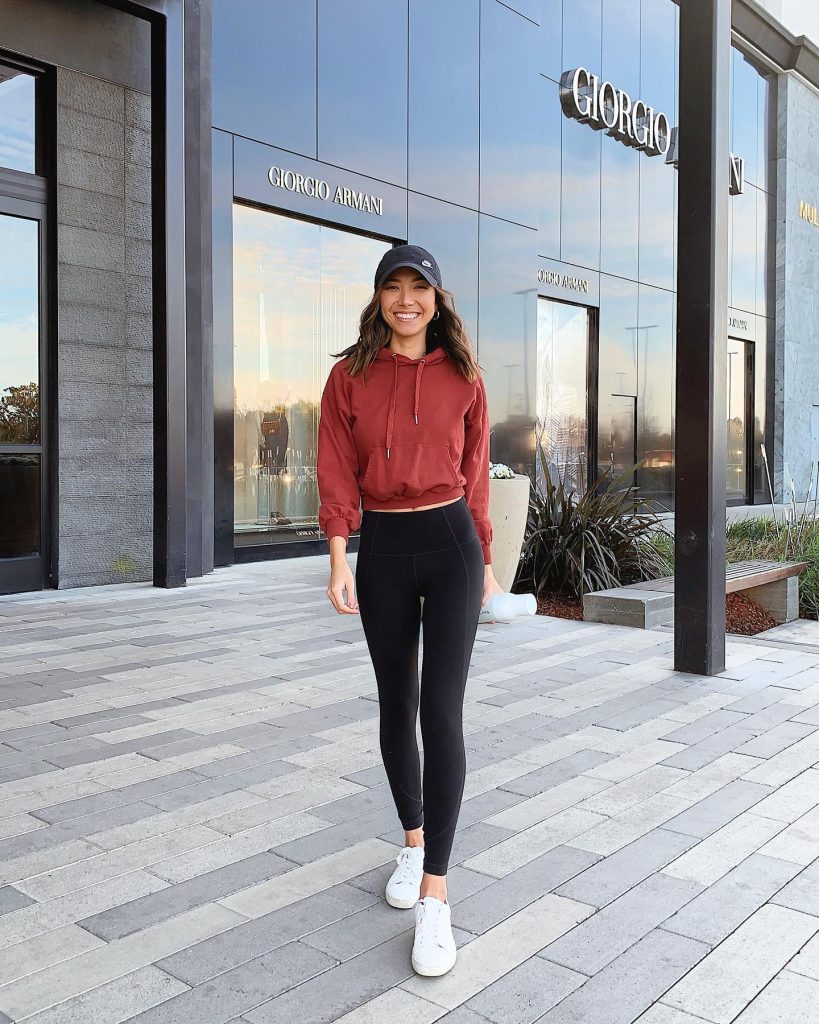 Rust Cropped Hoodie + Black Baseball Cap + High-Waisted Black Leggings