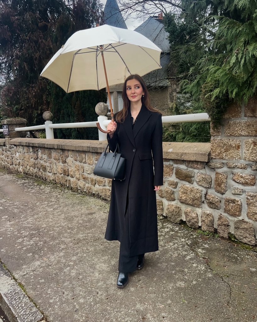 Black Maxi Coat + Black Trousers + Cream Umbrella